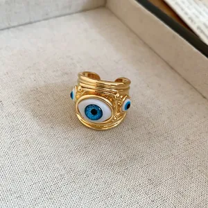 Close-up of a gold-toned adjustable open ring featuring a vivid blue evil eye design.