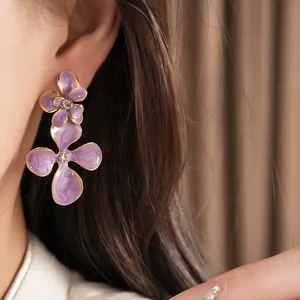Close-up of elegant purple enamel flower earrings with sparkling rhinestone centers