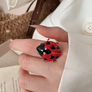 Detailed view of a cute red and black enamel ladybug ring with heart spots on a finger