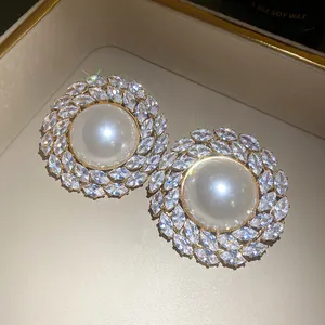 Detailed close-up showing vintage round pearl stud earrings with sparkling marquise zircon halo