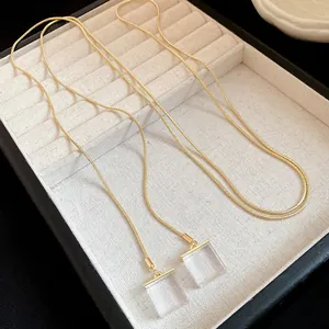 Elegant detail view of a gold snake chain necklace featuring transparent resin square pendants