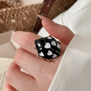 Close-up detail of a cute ladybug ring with black enamel and white heart patterns