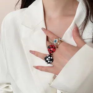 Detailed macro view of ladybug and evil eye rings worn on a hand over a white blazer