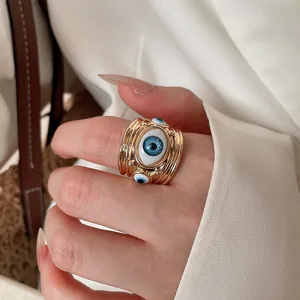 Detailed close-up of a gold-toned chunky ring with blue evil eye enamel jewelry