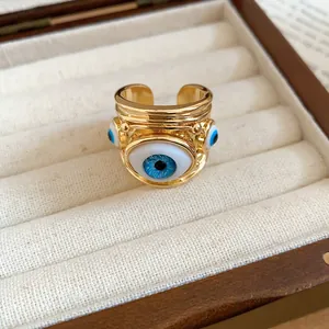 Close-up detail of a gold open ring featuring a blue evil eye design in a jewelry box