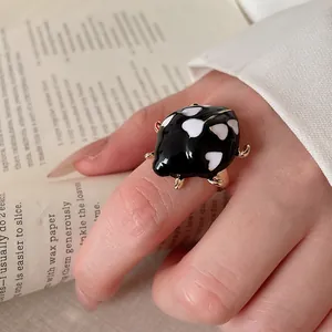 Close-up of heart-patterned black ladybug enamel ring on finger for a cute aesthetic