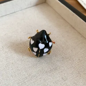 Detailed view of a cute black enamel ladybug ring featuring white heart patterns