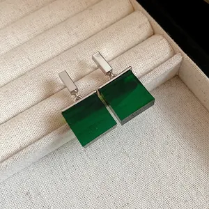 Close-up of elegant square emerald green resin earrings in a beige jewelry tray