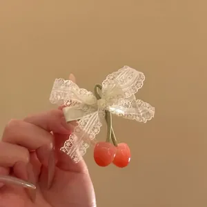 Detailed close-up of a sweet lace bow hair clip with translucent cherry charms