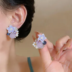 Detailed close-up showing elegant purple flower earrings with pearls and crystals.