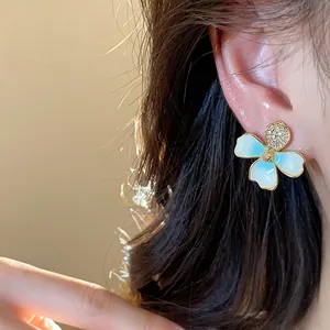Elegante primo piano di un orecchino a fiore con smalto blu e zirconi sull'orecchio.