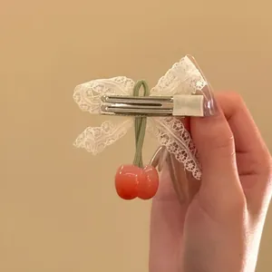 Detailed view of back metal clip on lace bow hair accessory with cherry charm