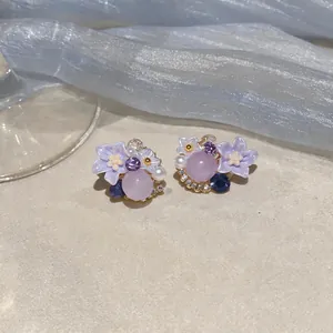 Macro view of exquisite purple flower stud earrings featuring tiny crystals and beads