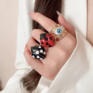 Detailed view of colorful enamel ladybug rings and golden evil eye ring on a hand