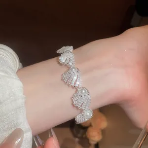 Detail view of an elegant pearl and shell-inspired bead bracelet worn on a wrist