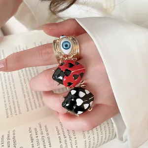Close-up of cute ladybug and evil eye adjustable rings with colorful enamel finish