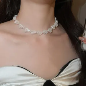 Close-up of elegant white pearl and shell choker necklace worn by model on neck.