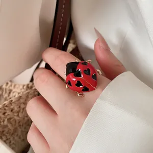Detailed close-up of a red ladybug open ring with heart-shaped spots on a finger