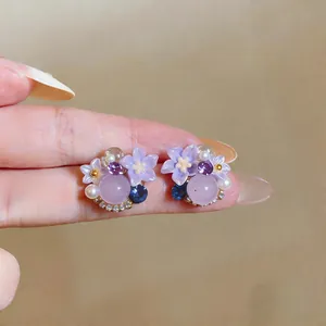 Detailed view of exquisite purple flower stud earrings with pearl and crystal accents