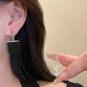 Close-up detail of vintage green square resin pendant earrings worn by an Asian model.
