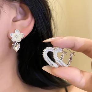 Detail view of asymmetric heart and flower earrings with pearl and crystal accents