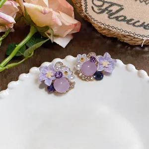 Detailed close-up of elegant purple flower cluster earrings with crystals and pearls
