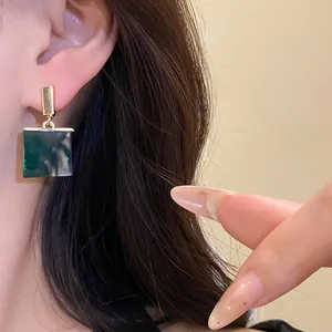 Close-up of retro square green resin pendant earrings on model for detail view