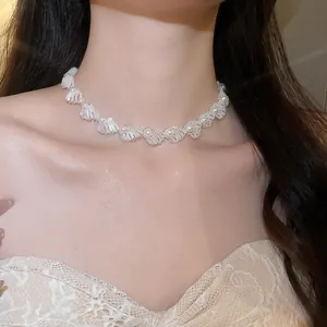 Elegant white beaded shell choker necklace with pearl accents worn by a female model