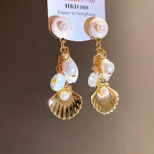 Elegantes pendientes de plata con perlas blancas, conchas doradas y flores de moda.