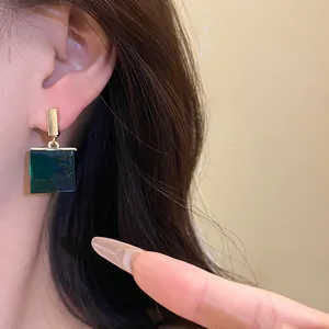 Detailed close-up view of vintage emerald green square resin pendant earrings on a model