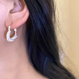 Close-up view of a heart-shaped silver earring with pearl inlay on a model's ear.