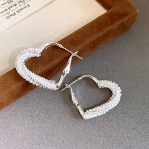 Close-up of elegant heart-shaped hoop earrings adorned with delicate white pearls.