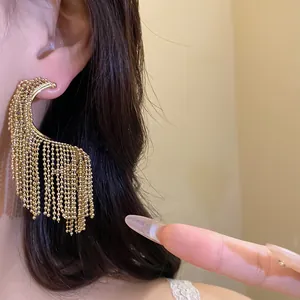 Primer plano de elegantes pendientes de borla dorados usados por una modelo