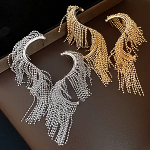 Primer plano de elegantes pendientes de borlas con flecos dorados y plateados en cuero
