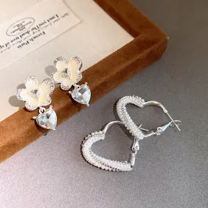 Detailed view of pearl heart hoops and floral crystal drop earrings on display