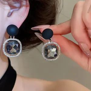 Detail view of geometric earrings with grey faceted stone and matte black top.