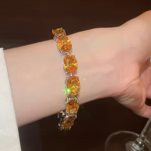 Close-up of luxury 18k gold plated bracelet featuring vibrant orange zircons on wrist.