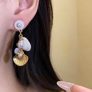Primer plano de pendientes colgantes de flor con perla y concha