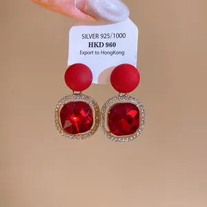 Macro view of elegant red faceted crystal earrings featuring a sparkling diamond halo