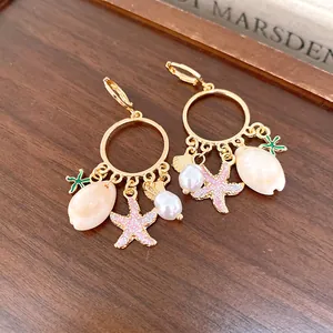 Detalle de pendientes de aro dorados con colgantes de conchas y estrellas de mar