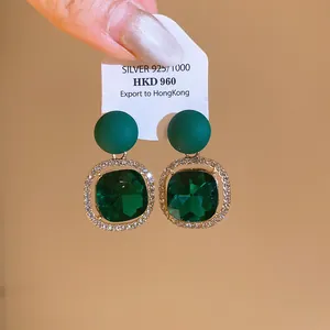 Emerald green cushion-cut stud earrings with rhinestone halo and silver 925 tag