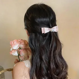 Eleganter rosa Stoff-Haarclip mit Schleife und Perlen, getragen von einem Modell