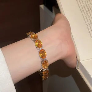 Close-up of 18k gold plated bracelet with oval orange zircons on wrist.