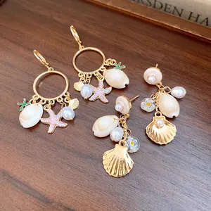 Detalle de pendientes dorados elegantes con conchas, perlas y colgantes de estrella