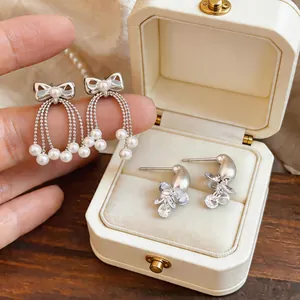 Close-up of elegant silver bow earrings with pearl tassels and crystal accents in a gift box