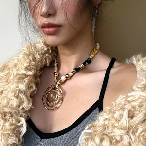 Detail view of a golden irregular wire-wrapped resin pendant necklace on a model