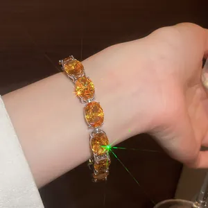 Close-up of elegant gold plated bracelet with sparkling oval orange zircons on wrist