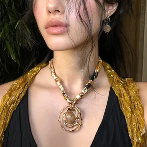 Detailed view of an elegant gold-toned resin circular pendant necklace worn by a fashion model