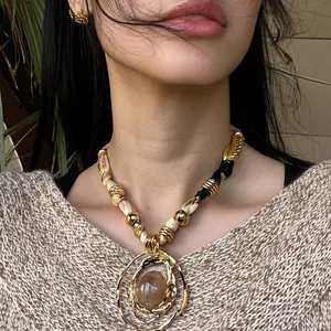 Bohemian style fabric wrap necklace with a large round resin pendant in vintage gold