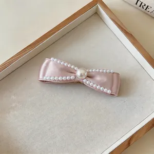 Elegante Nahaufnahme einer rosa Satin-Schleifen-Haarspange mit feinem Perlenbesatz
